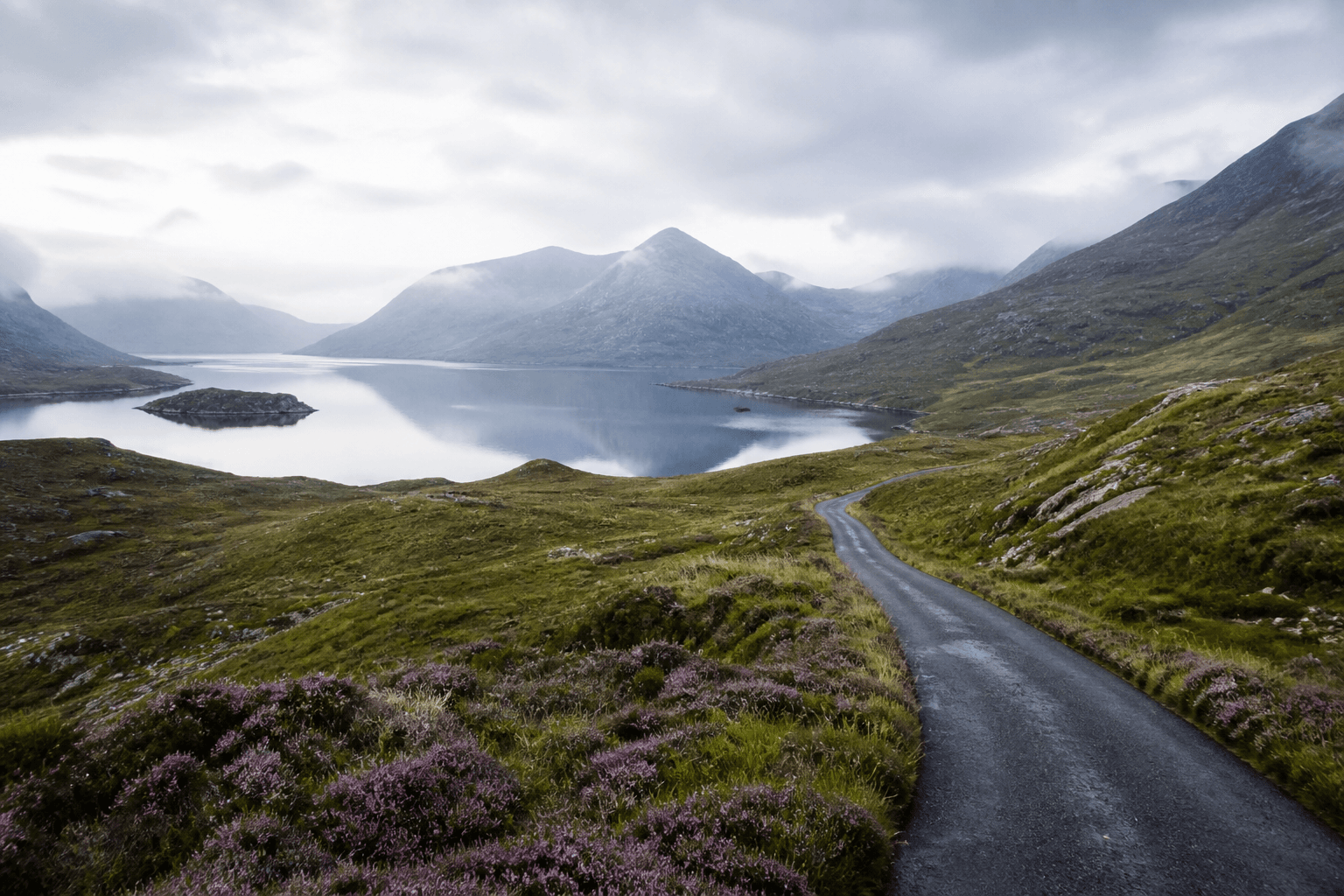 Narrow Highlands road through misty Scottish glens